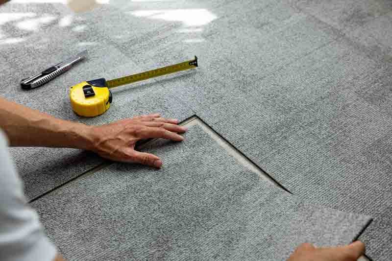 installer-laying-carpet-tiles-on-floor